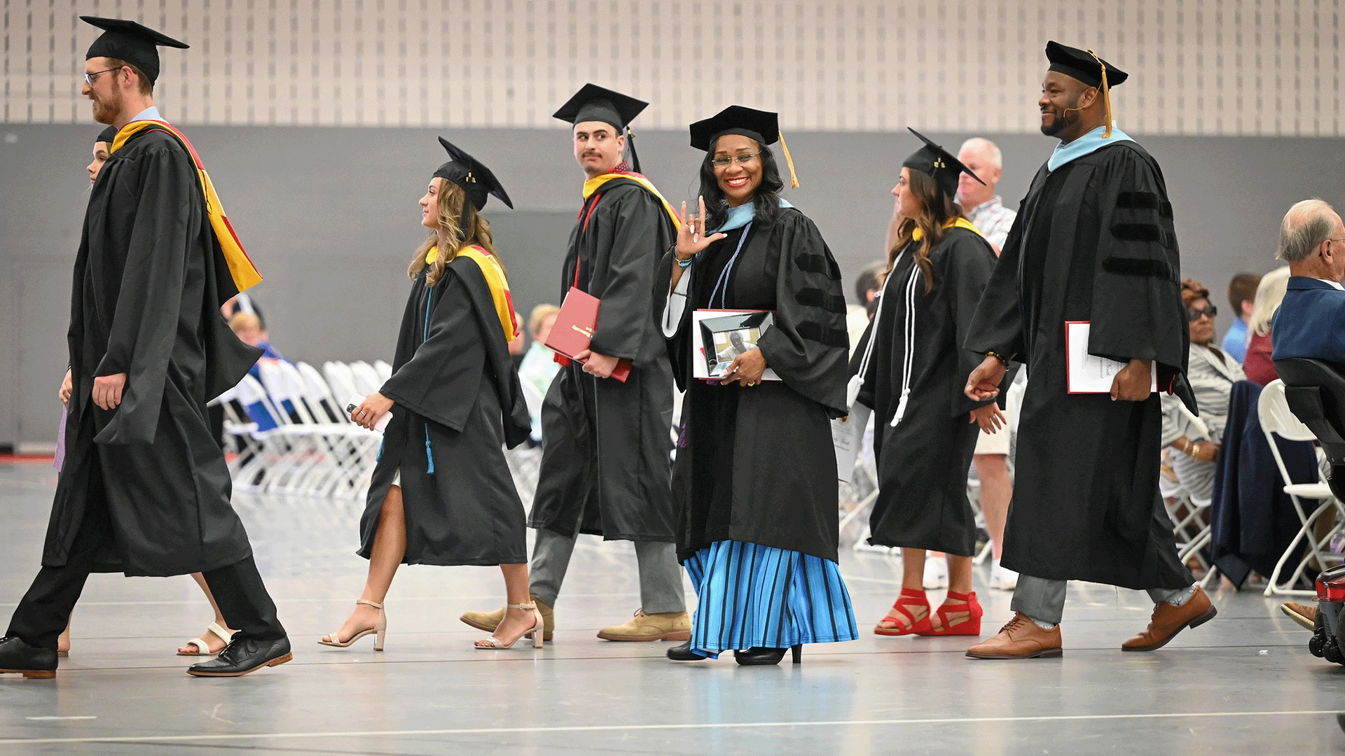 Students in commencement regalia process together.