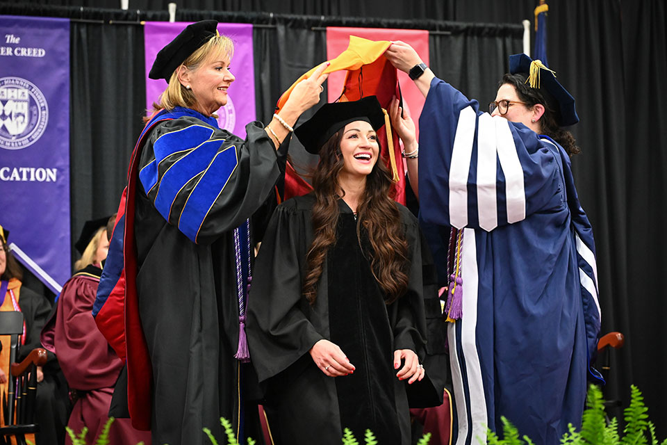 A doctoral candidate is hooded during the Wegmans School of Nursing ceremony.