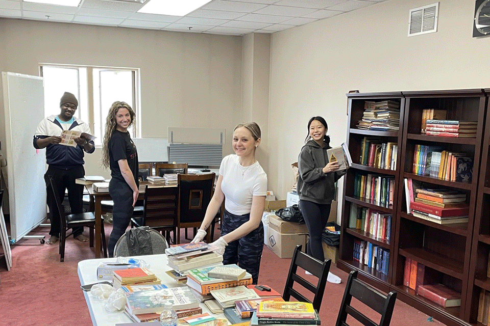 Students sort books at the Hindu Temple of Rochester for the Wegmans School of Pharmacy Service Day.