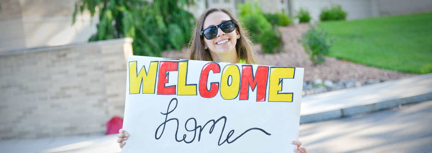 Student holding Welcome Home sign.